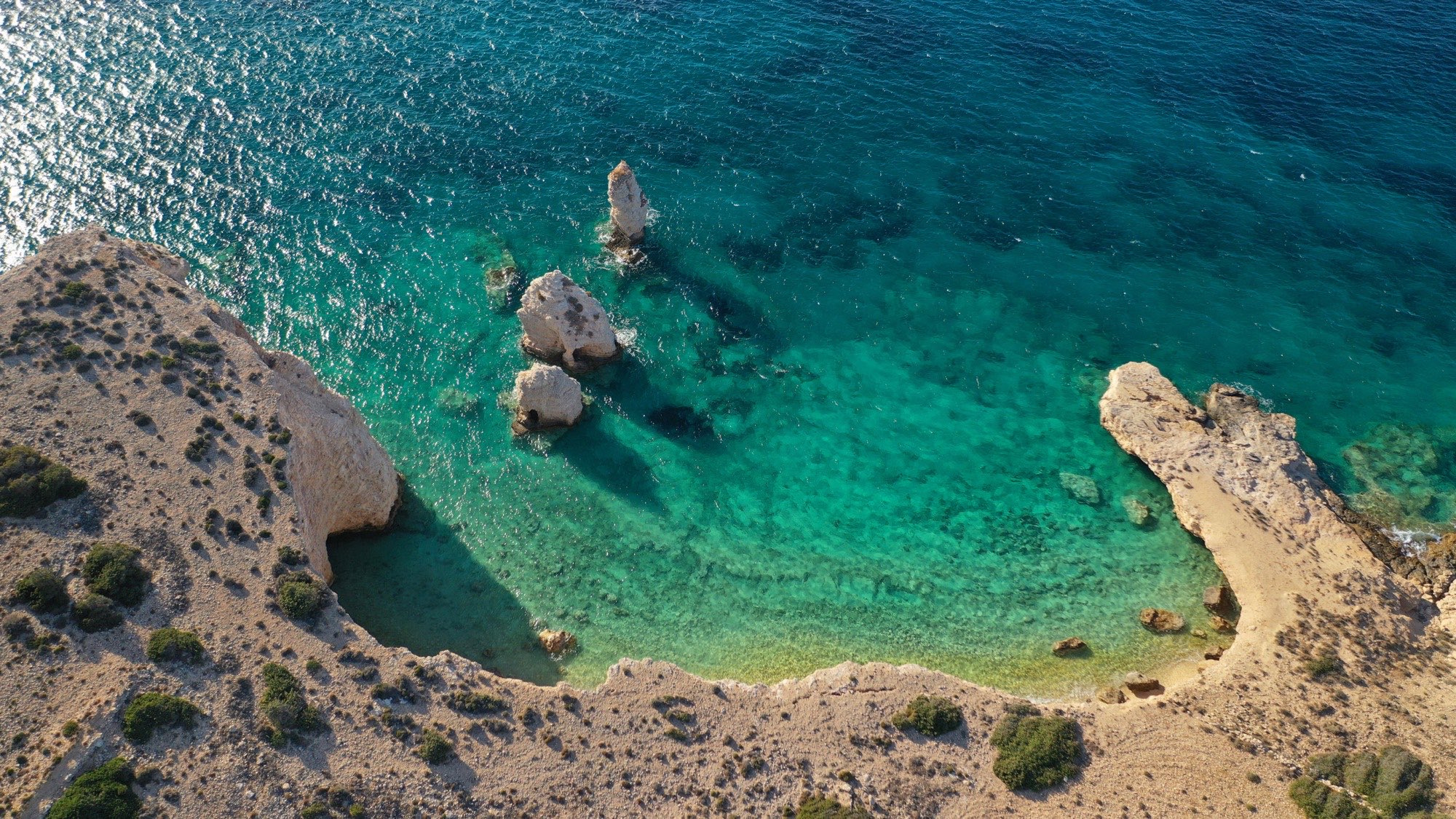 Vue aérienne d'une crique isolée de Kato Koufonissi, eau turquoise et roche claire.